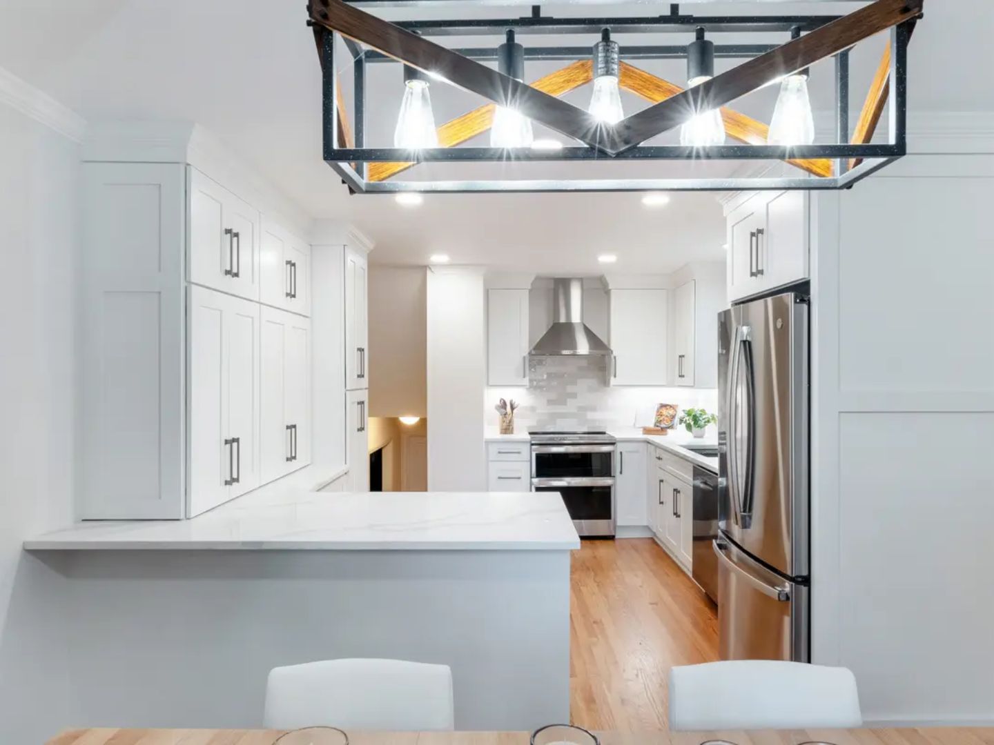 Modern kitchen remodel with white shaker cabinets and farmhouse light fixture by Mendez and Sons